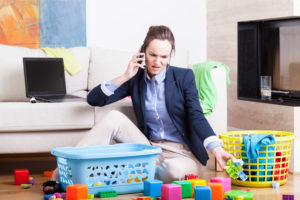 Young woman cleaning up toys and working from home